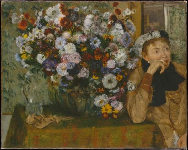 A Woman Seated Beside A Vase of Flowers